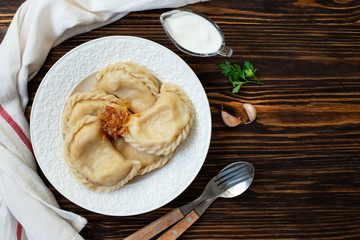 Vareniki or pyrohy, varenyky, dumplings traditional east european pastry dish stuffed with potatoes served with sour cream and caramelized onions. Ukrainian, Polish, Russian cuisine. Wooden background
