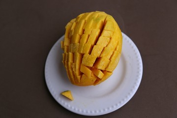 Large sugar tropical mango fruit with no skin ready to eat on a white plate view from above