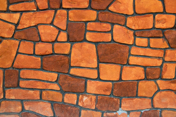 Texture of brown and black stone blocks closeup. Old brown bricks. The background wall has a beautiful pattern. The dark color of the surface makes the fence strong.
