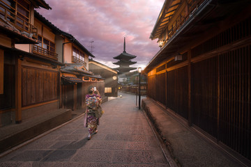 Kyoto, Japan - November 4 2018: A woman dressed like a Maiko taking a photo of Yasaka Pagoda with sun rays at sunrise in Higashiyama-ku, a traditional street in Gion district, Kyoto. 
