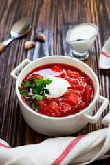 Borscht traditional beetroot soup, Ukrainian and Russian national cuisine. Borscht served in a white bowl with sour cream and parsley on a wooden table. Close-up. Vertical