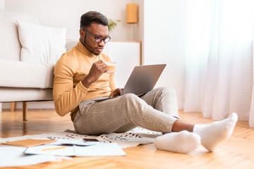 Serious Freelancer Guy Working On Laptop Having Coffee At Home