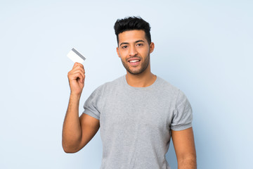 Young handsome man over isolated background holding a credit card