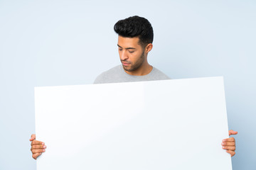 Young handsome man over isolated background holding an empty white placard for insert a concept