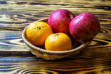 fresh fruits in a straw basket on a wooden background, top view, selective focus