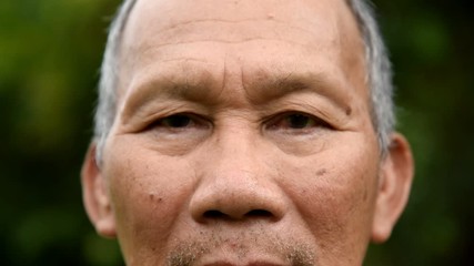 Closeup Asian Senior man is looking at the camera at park outdoor. - Powered by Adobe