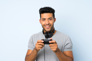 Young handsome man over isolated background playing at videogames