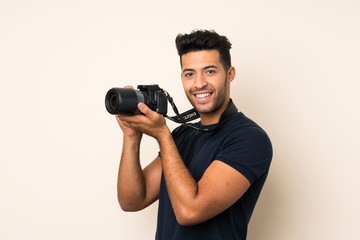 Young handsome man over isolated background with a professional camera