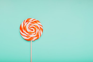 Orange Lollipop on blue background with soft contrast. Minimal concept with copy space.