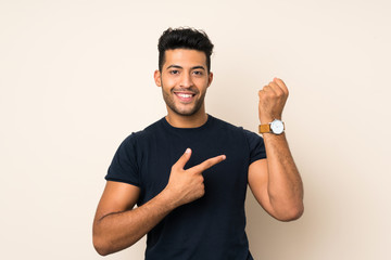 Young handsome man over isolated background showing the hand watch