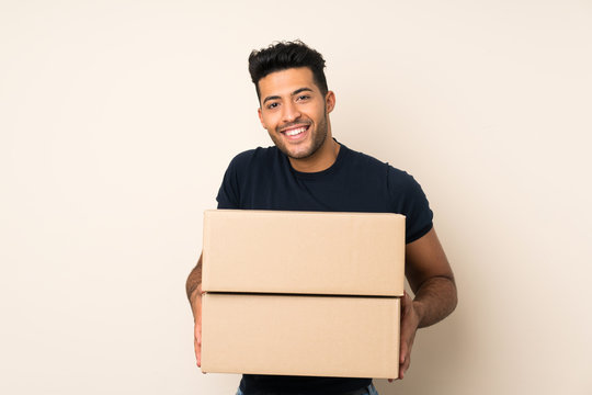 Young handsome man over isolated background holding a box to move it to another site