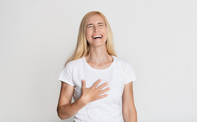 Emotional middle-aged woman laughing and touching her chest