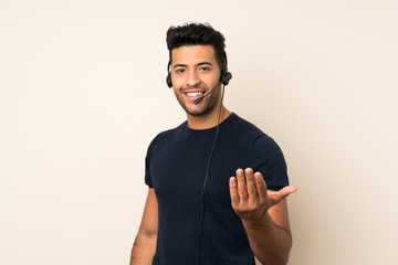 Young handsome man over isolated background working with headset doing coming gesture