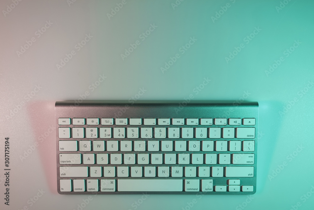 Aufkleber beautiful modern silver keyboard in the color light on a table and night background. top view.