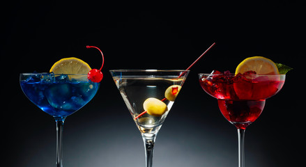 Two colorful cocktails and dry martini with green olives.