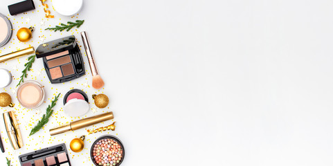 Makeup mascara foundation cream lipstick eyeshadow blush balls and New Year decorations gold Christmas balls confetti stars fir branches on light background Flat lay top view. Cosmetics, holiday Xmas