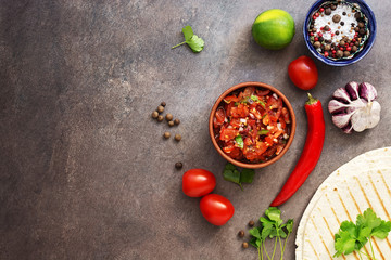 Traditional mexican homemade salsa sauce,spices and tortilla on a dark rustic background. Top view, flat lay, copy space.