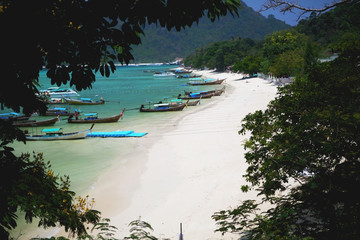 View of the beach with boats through the trees. Phi-Phi island Thailand.