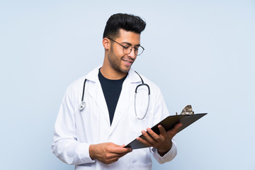 Young doctor man over isolated blue wall