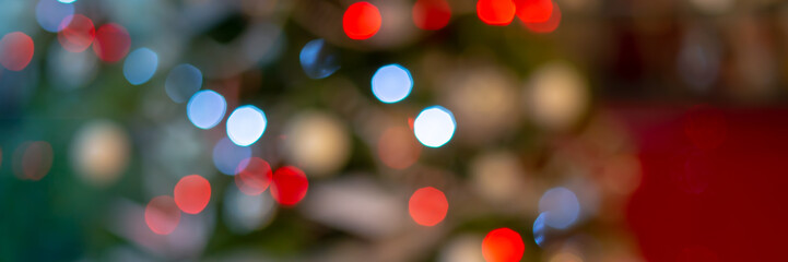 Panoramic web banner of blurred green and red bokeh holiday lights at night, christmas tree...