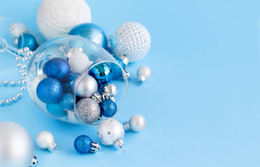Christmas baubles in a wine glass on a light blue background
