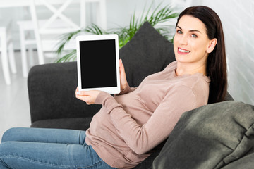 beautiful smiling pregnant woman holding digital tablet with blank screen