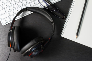 headphones and office supplies with computer keyboard on office desk