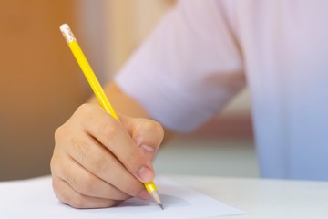 Student drawing something on white paper by yellow pencil