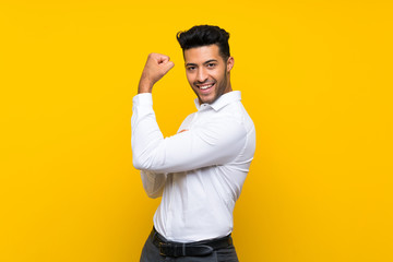 Young handsome man over isolated yellow background making strong gesture