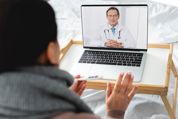 cropped view of diseased woman having online consultation with male doctor on laptop