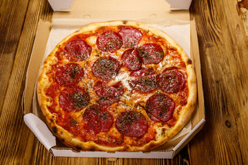 Delicious fresh pizza in cardboard box on a wooden table. Concept for home delivery of food, fast food, delivery of pizza