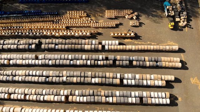 Aerial flying over warehouse of wooden coils designed for electric cable or optical fiber. Reels of different sizes and colors are lying on the street, the truck is unloading. Taken by drone at autumn