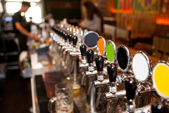 Lot of vintage Golden beer taps in the bar with the bartender in the background