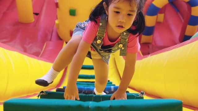 kids playing the air castle at temple festival. 4 years girl are climbing slope wall to top of the wall. children love air castel because they feel relax and fun.