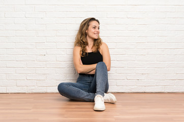 Fototapeta na wymiar Young blonde woman sitting on the floor looking to the side
