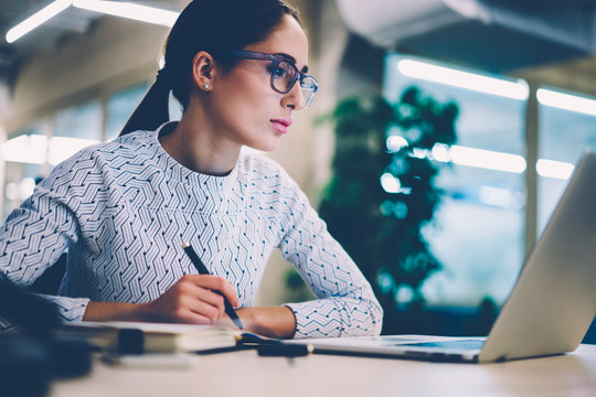 Concentrated businesswoman analyzing information from networks reading news from netbook sitting at desktop,female employee checking email box planning project strategy using modern technologies