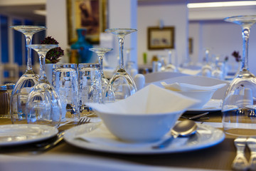 glasses plates and Cutlery on restaurant table in white close-up, traditional Greek restaurant, Europe, Greece.