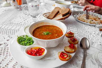 Tomato soup with pepper, parsley spices in a white plate in a restaurant serving with a set of canapes. Close up