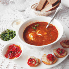 Tomato soup with pepper, parsley spices in a white plate in a restaurant serving with a set of canapes. Close up