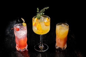 Three alcoholic cocktail with juice garnished with cherry and jalapeno pepper planted for a long time.