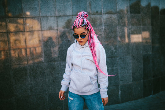 City portrait of handsome hipster girl with colored afro braids wearing gray blank hoodie or hoody with space for your logo or design. Mockup for print
