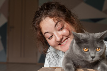 Beautiful girl playing with a gray cat
