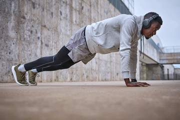 Athletic man is exercising near the grey wall