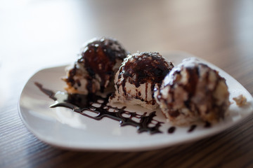 Round candies in dark chocolate on a plate. Dessert, sweets