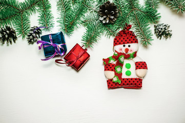 Christmas decorations. Frame of branches of Christmas tree with snowman, pine cones and gift on white background with space for text. Selective focus