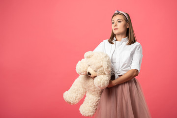 attractive and stylish woman holding teddy bear isolated on pink