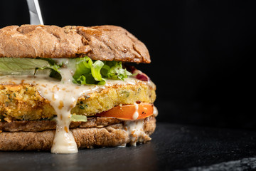 Huge veggie burger with potato patty, salad, cheese.