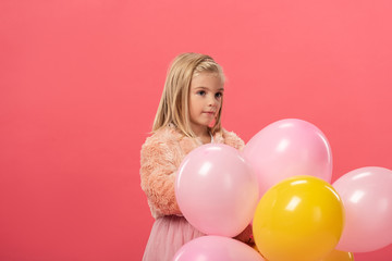 Fototapeta na wymiar cute and stylish kid holding balloons isolated on pink
