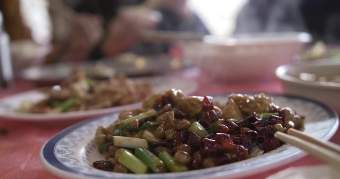People eating the traditional Chinese food Kung Pao Chicken with chopsticks. Close-up in 4K.