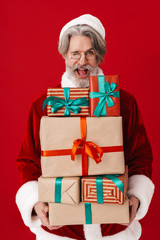 Image of joyful gray-haired old Santa Claus man holding gift boxes